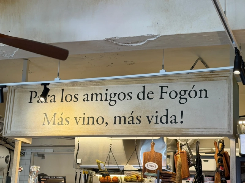 フォゴンの店内。キッチンの上に「Para los amigos de Fogón」「Más vino, más vida!」と書かれた大きなサインが掛かっている