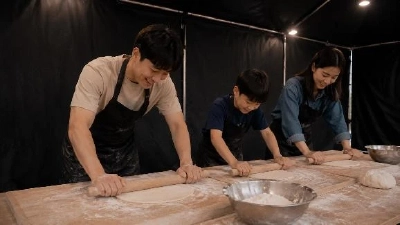 粉をふった台の上で大人と子どもが麺棒を使って生地をのばしている体験ブース