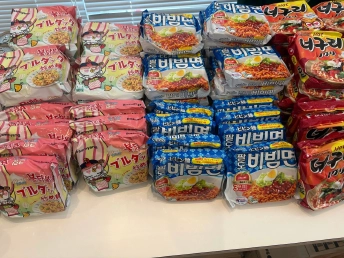 ピンク、青、赤のパッケージの韓国インスタント麺が並ぶテーブル