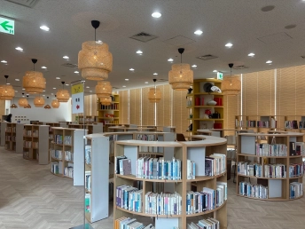編み込みのペンダントライトの下に、曲線を描く本棚が並ぶ図書室