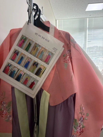 番号付きの韓服一覧表が掛けられた、花の刺しゅう入りのピンクの韓服