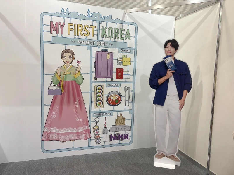 「MY FIRST KOREA」のイラストパネルの横に、青い冊子を手にした等身大パネルが立つフォトゾーン