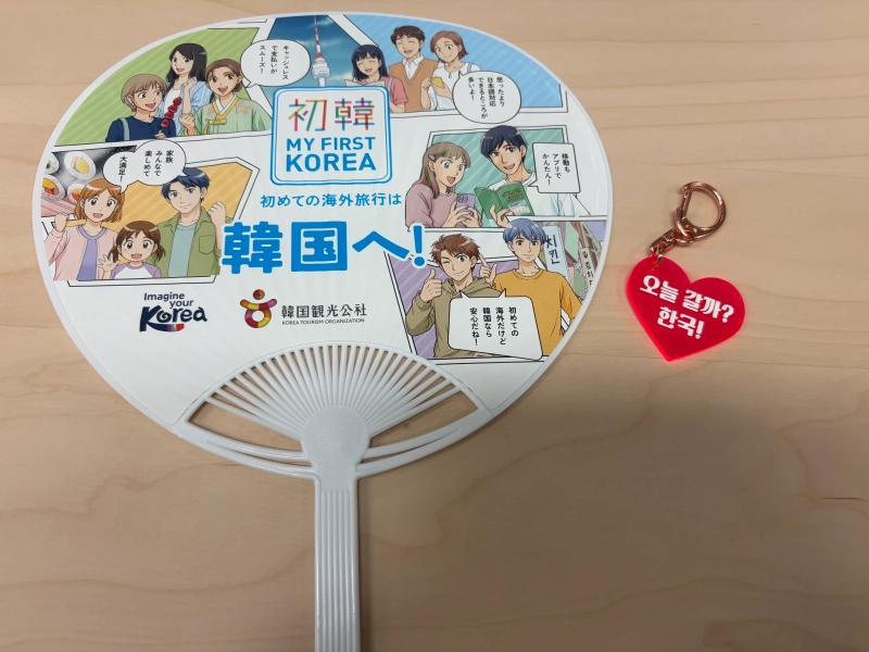 「MY FIRST KOREA」のイラストが描かれた韓国観光公社のうちわと、「오늘 갈까? 한국!」と書かれた赤いハートのキーホルダー